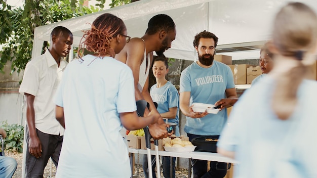 A diverse group of people standing in line to register to vote at a community center, with volunteers assisting them at tables with registration forms and informational pamphlets.
