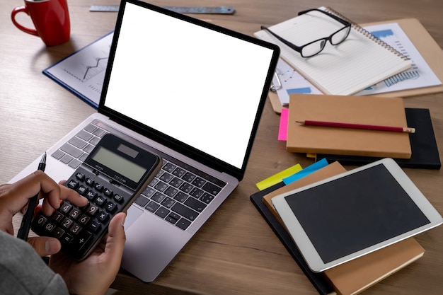 A person using a calculator with papers and a laptop nearby, symbolizing the process of calculating MAGI (Modified Adjusted Gross Income). The background is a home office setting, suggesting personal financial planning.