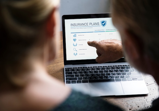 A person sitting at a desk, using a laptop to compare health insurance plans. The screen shows a side-by-side comparison of COBRA and ACA plans, highlighting the costs, coverage, and benefits.