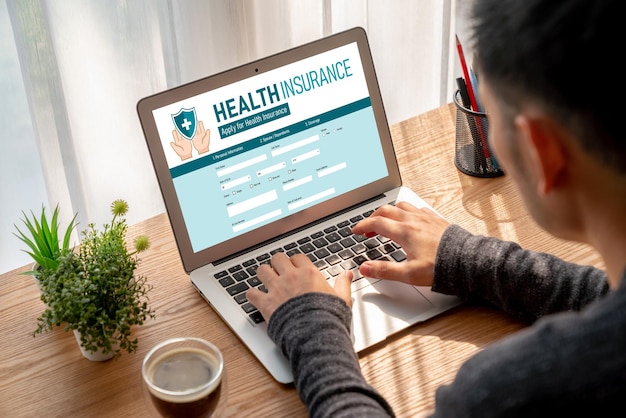 A person filling out an online health insurance application on a laptop, with various documents related to qualifying life events (marriage certificate, birth certificate, job termination letter) neatly organized on the desk.
