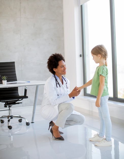 A doctor in a white coat shaking hands with a patient in a modern medical office. The scene emphasizes the importance of the primary care physician in an HMO plan.