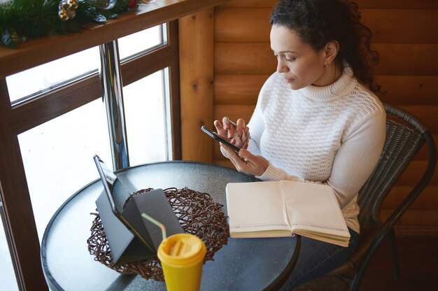 A person on the phone with their insurance company, taking notes on a notepad. The background is a cozy, inviting home setting.