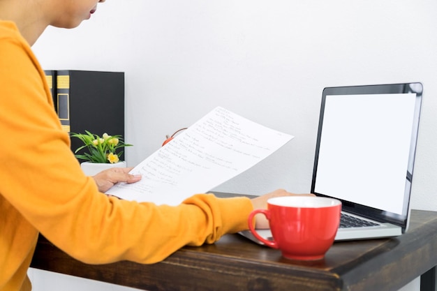 A person sitting at a desk, organizing documents and papers, with a laptop displaying a LIHEAP application form. The setting is a home office, emphasizing the preparation needed for the application.