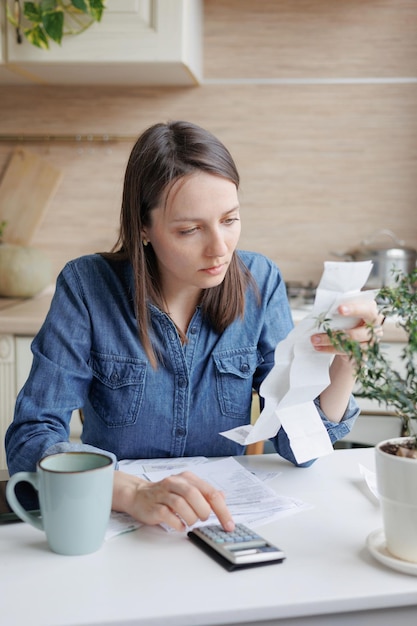 A person sitting at a table reviewing bills and receipts with a calculator, symbolizing careful budgeting to manage TANF benefits during inflation.