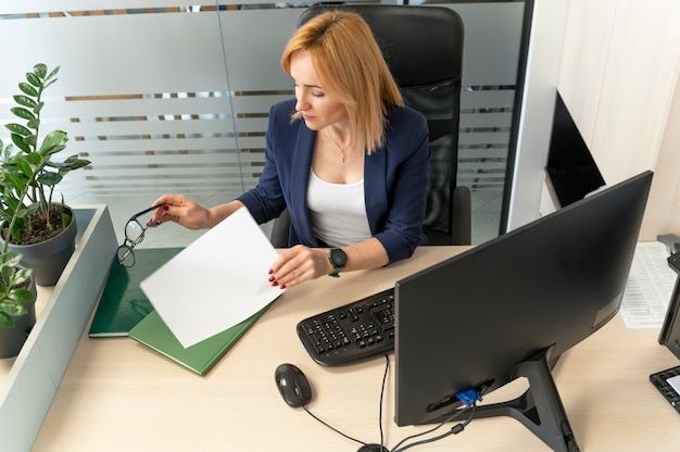 A person sitting at a desk, filling out an application form with the help of a CAA staff member. The staff member is pointing to a section of the form and explaining it clearly. The atmosphere is supportive and encouraging.