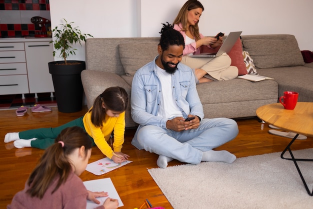 A diverse family (two parents and two children) planning their grocery list at home, with a laptop displaying online grocery prices. They are comparing prices and discussing affordable meal options.