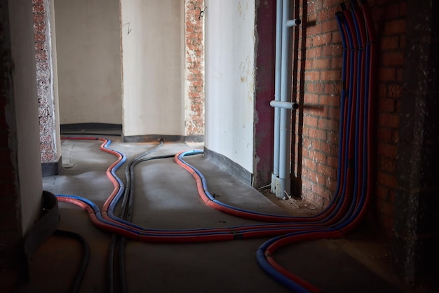 A close-up of a geothermal heat pump being installed in the basement of a home, showing the pipes and connection points. The setting is a typical American home basement.