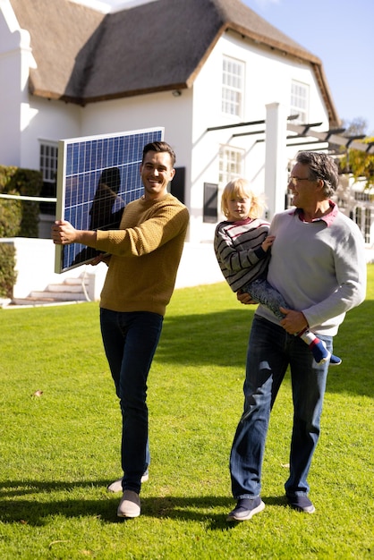 A family standing in front of their home, smiling, with solar panels visible on the roof. The image conveys a sense of pride and environmental responsibility.