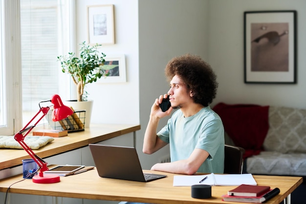 An interior shot of a home office with a person sitting at a desk, reviewing documents related to renewable energy tax credits on a computer screen. The scene conveys a sense of research and financial planning.